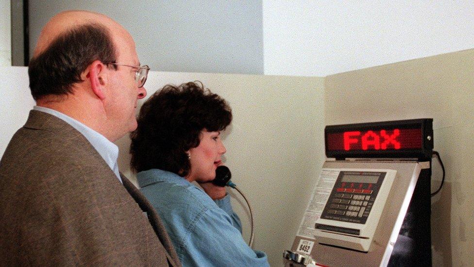 People queue to use a fax machine at Denver International Airport in 2000