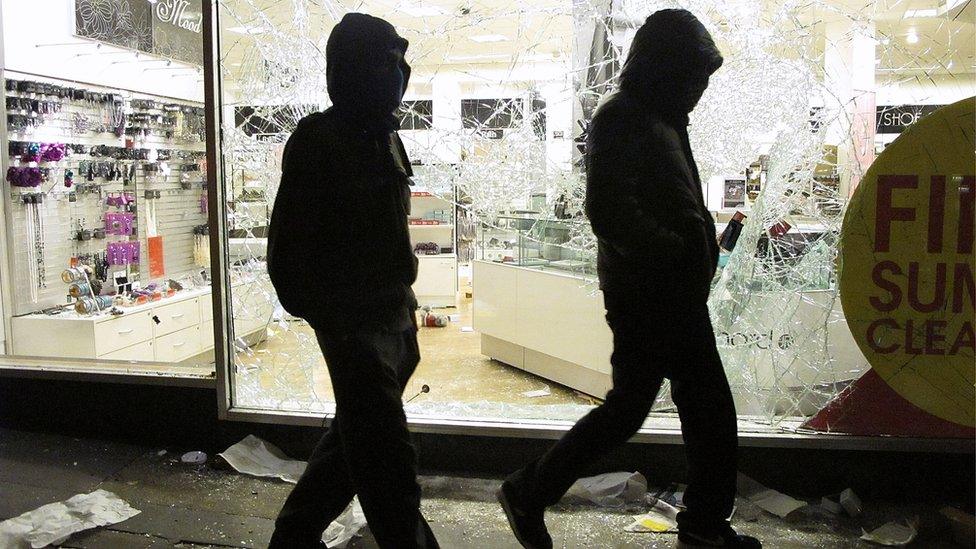 Youths walk past the looted Debenhams store in Clapham Junction, on 8 August 2011