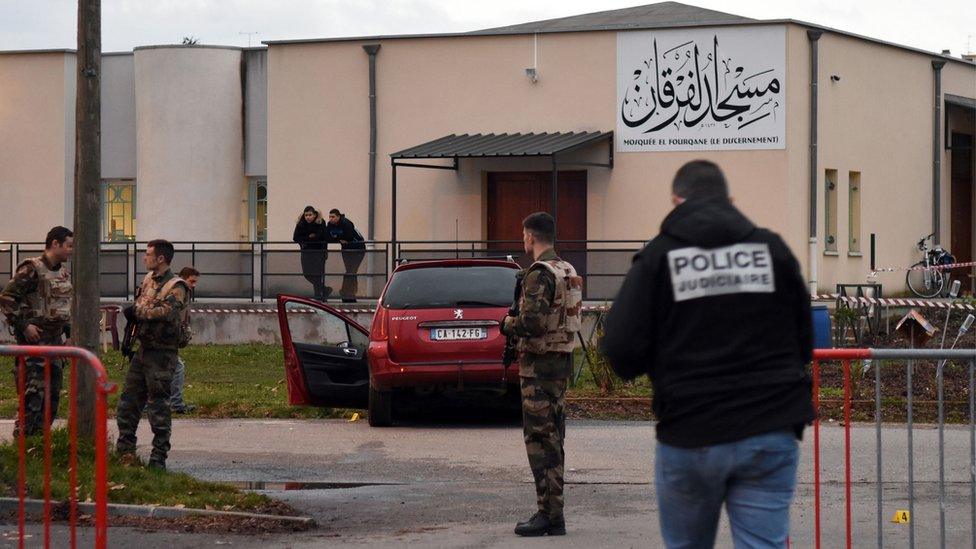 French police officers and soldiers stand near a red car in front of the mosque of Valence, southeastern France, on January 1, 2016,