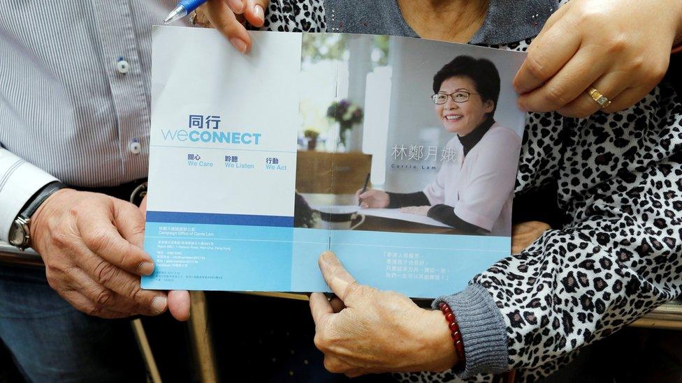 Carrie Lam's supporters hold an election platform as they wait for Lam during her visit in Hong Kong on 23 March