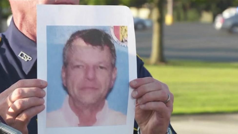 A police officer holds an image of John Houser at a news conference in Lafayette. Louisiana - 24 July 2015