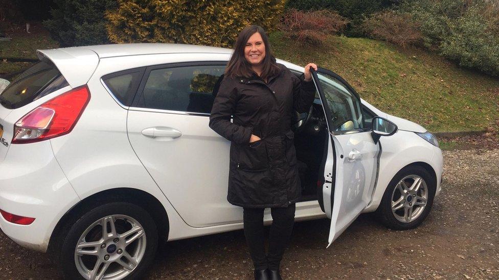 Karen Aycan standing with the car she teaches people to drive in