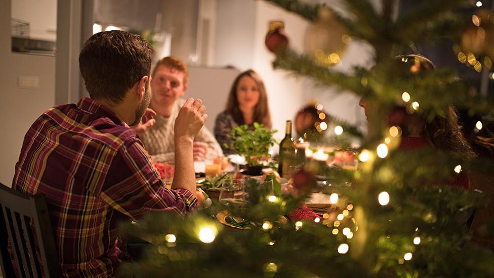 A festive meal with Christmas tree and people around a table