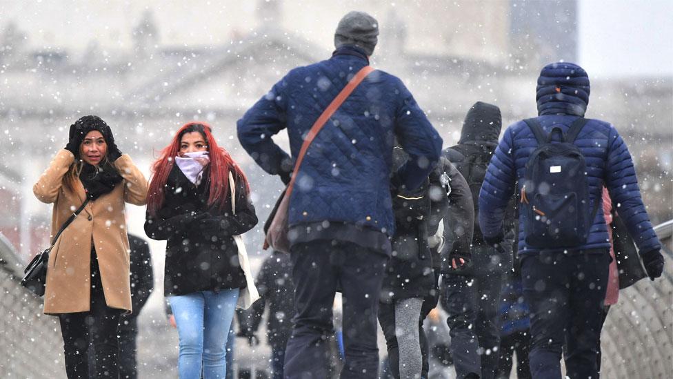 Commuters cross Millennium Bridge in London in the snow