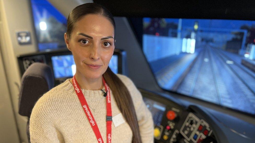 Lottie Hart, a train depot driver who works for Greater Anglia, standing inside a training simulator.