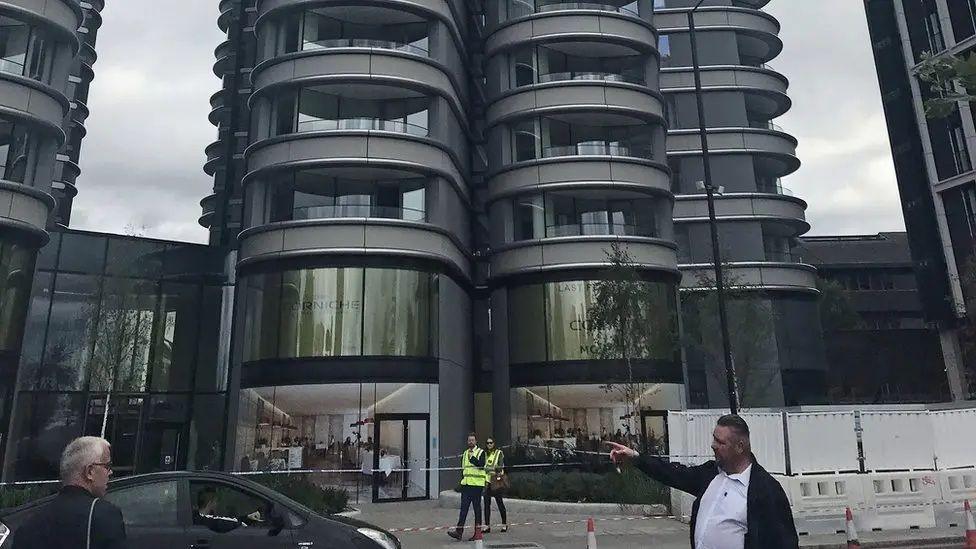 Police tape and two officers can be seen at the foot of a tower block