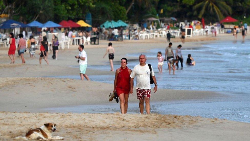 Tourists walking along a beach in Mirissa, Sri Lanka