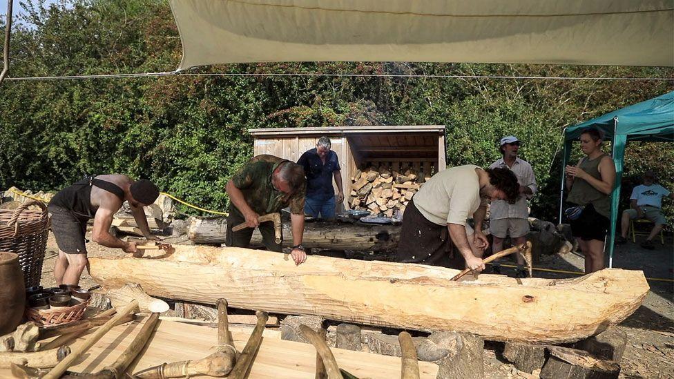 Six volunteers working on or discussing a log boat, Stanwick Lakes