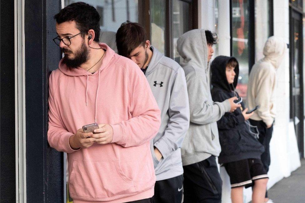 People queue for haircuts at a barber's shop in Wellington, New Zealand