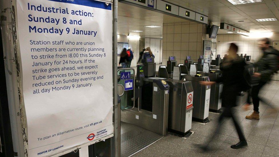 Commuters walk past a sign announcing details of the strike