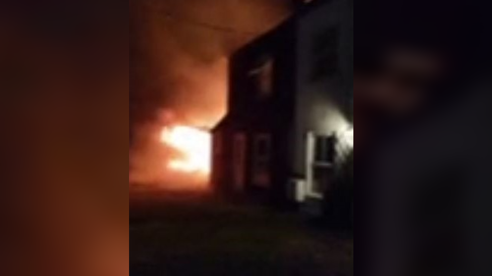 Orange flames coming out the left of a house. 
