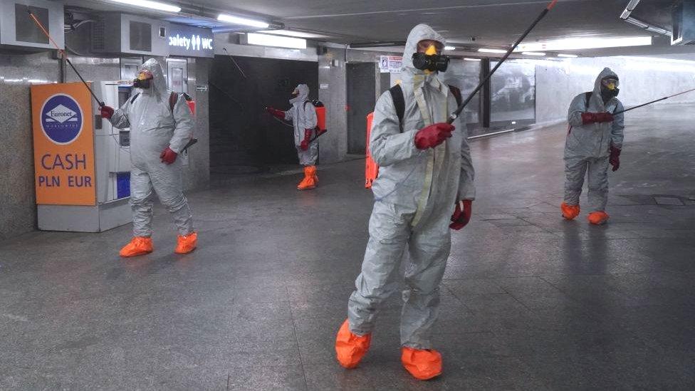 Polish workers disinfecting a car park