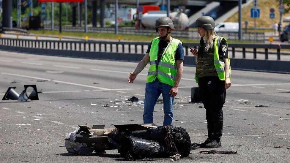 Police officers stand next to missile debris in Kyiv