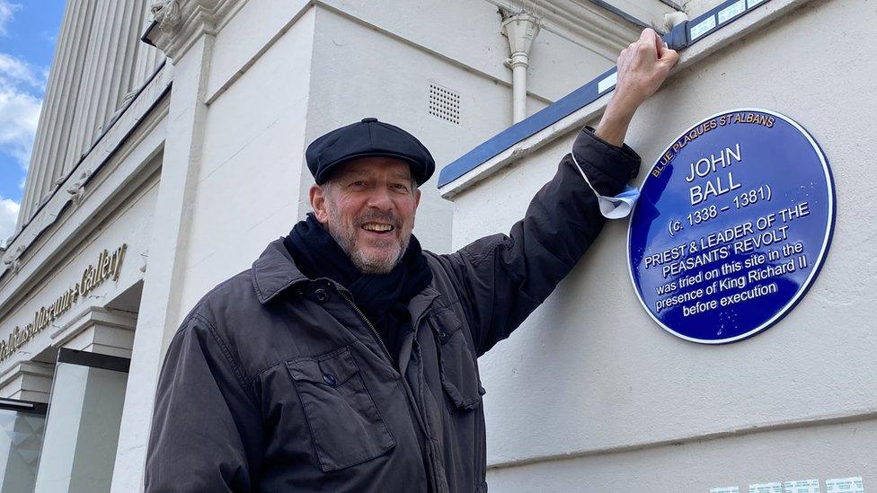 Tim Boatswain standing next to a blue plaque that has been unveiled to John Ball the leader of the Peasants' Revolt in 1381