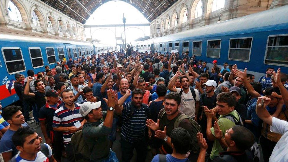 Dozens of migrants gesture as they stand in the main Eastern Railway station in Budapest, Hungary, on 1 September 2015.