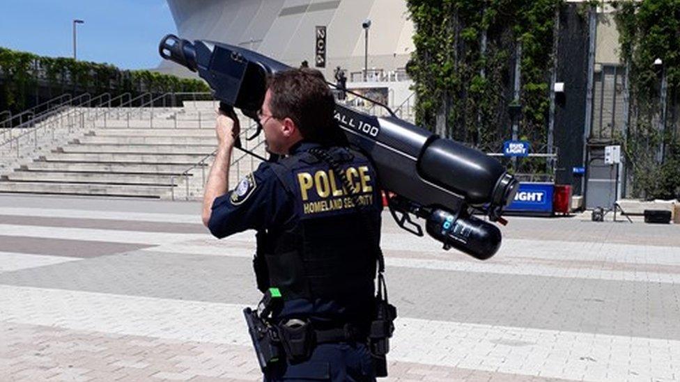 A New Orleans police officer shoulders a drone capture "gun"