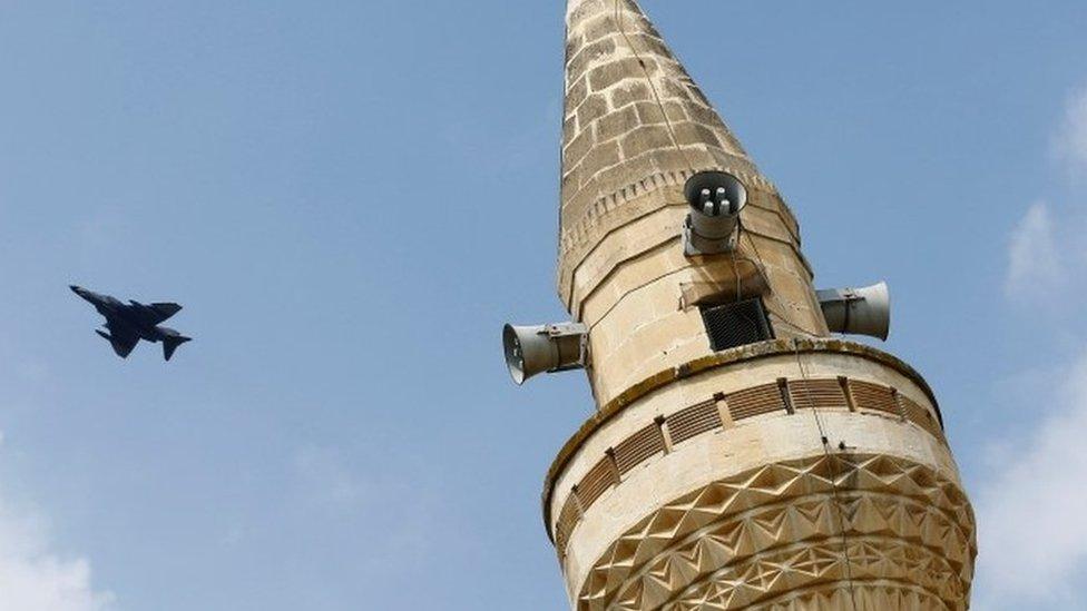 A Turkish Air Force F-4 fighter jet flies over a minaret after it took off from Incirlik air base (12 August 2015)