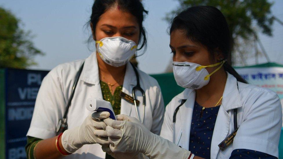 File photo showing two Indian doctors checking a thermometer