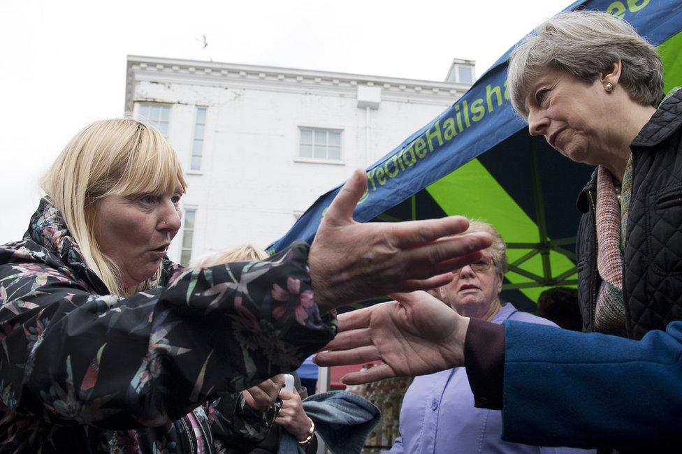 A woman speaks to Theresa May