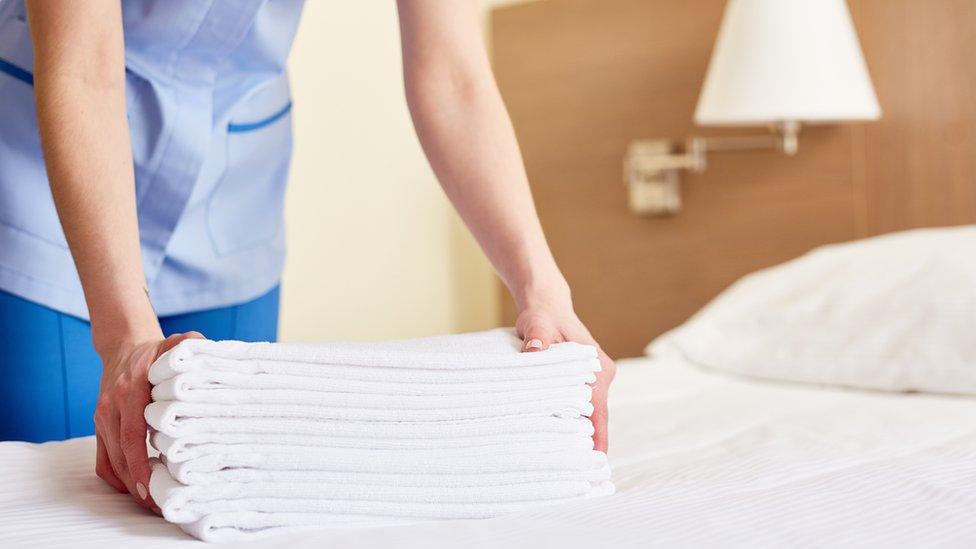 Chambermaid placing towels on bed