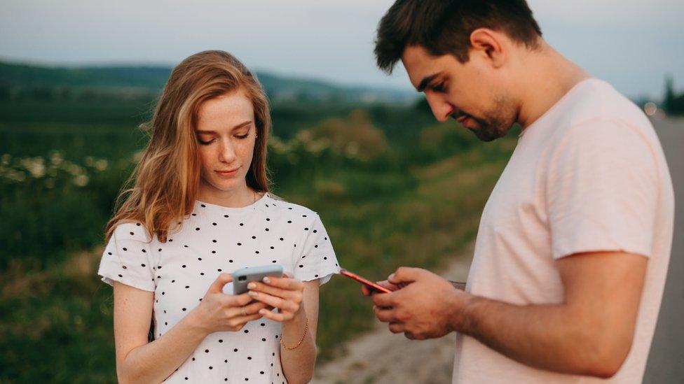 Man and woman looking at mobile phones