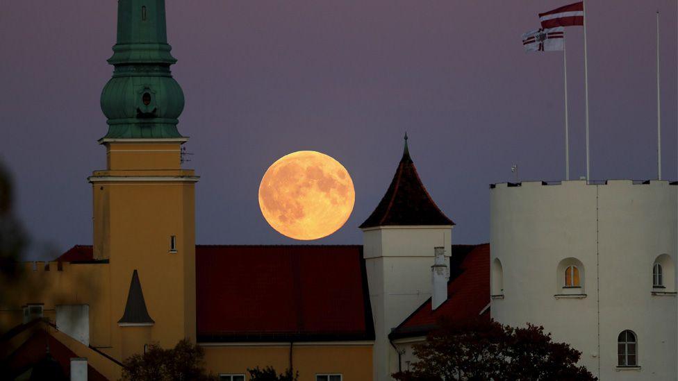 moon rises over latvia buildings