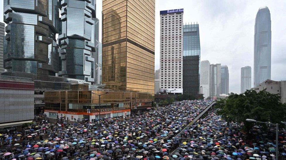 Protesters shelter under umbrellas during a downpour as they occupy roads near the government headquarters in Hong Kong on June 12, 2019.