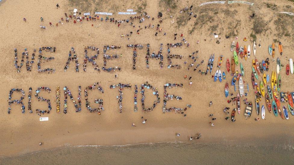 An aerial shot of protestors spelling out we are the rising tide