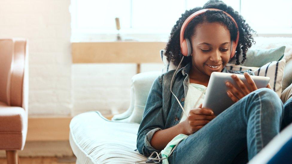 A girl watches something on her tablet