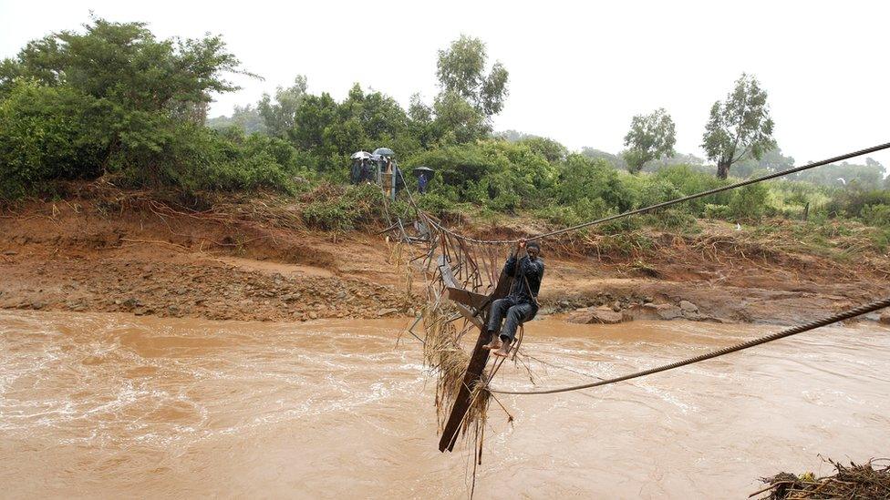 A man crosses a flooded Umvumvu river in Chimanimani, Zimbabwe - 18 March 2019