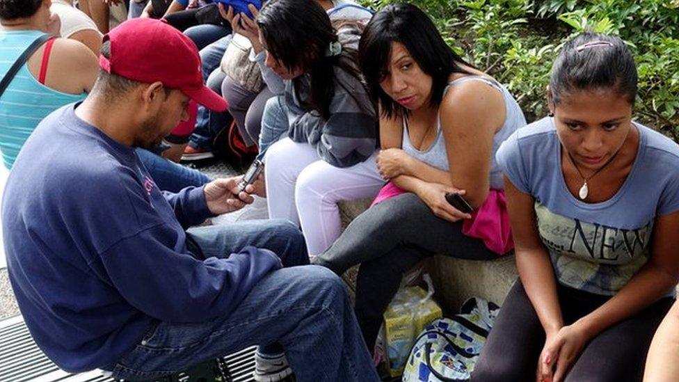 people queue to try to buy groceries and goods outside a supermarket in Caracas on 11 November