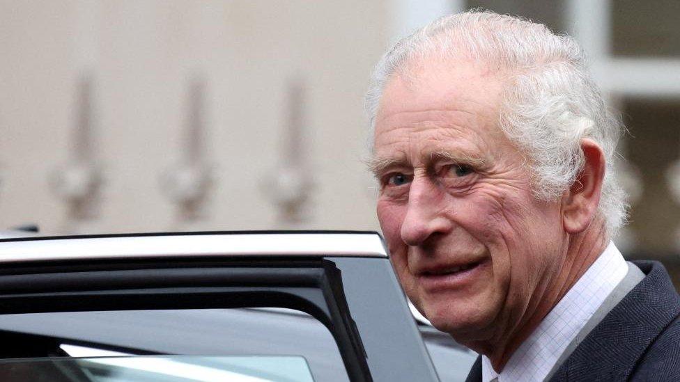 King Charles seen looking toward the camera as he gets into a car