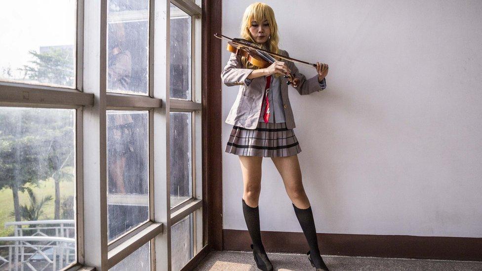 Cosplayer playing a violin, wearing a Japanese schoolgirl costume