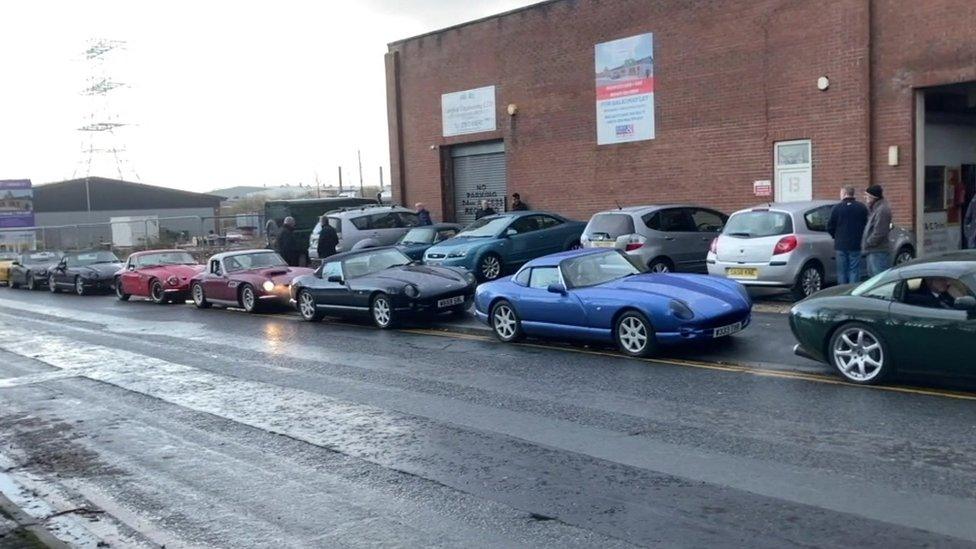 Sports cars parked in street outside factory