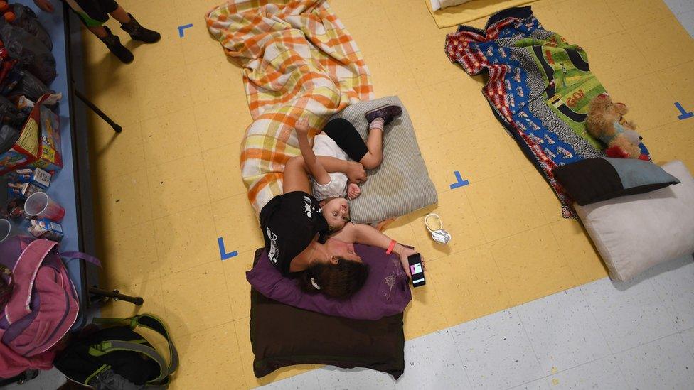 Jennifer Miller and her daughter Jubilee rest laying on the floor of a makeshift shelter at the Timberlin Creek Elementary School in St. Augustine, Florida, on October 6, 2016