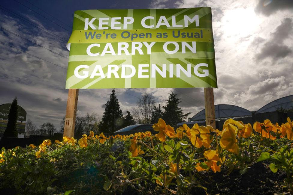 A sign tells people to "Keep calm and carry on gardening"