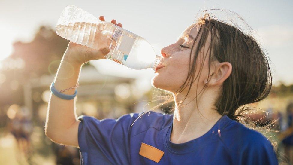 girl drinks bottle of water