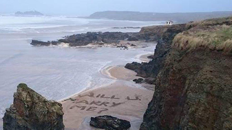 "Will you marry me?" written in the sand