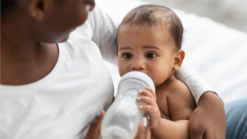 Mum feeding her child from baby bottle