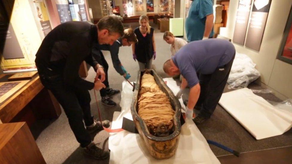 Nesyamun's mummified remains being lifted out of a coffin at Leeds City Museum