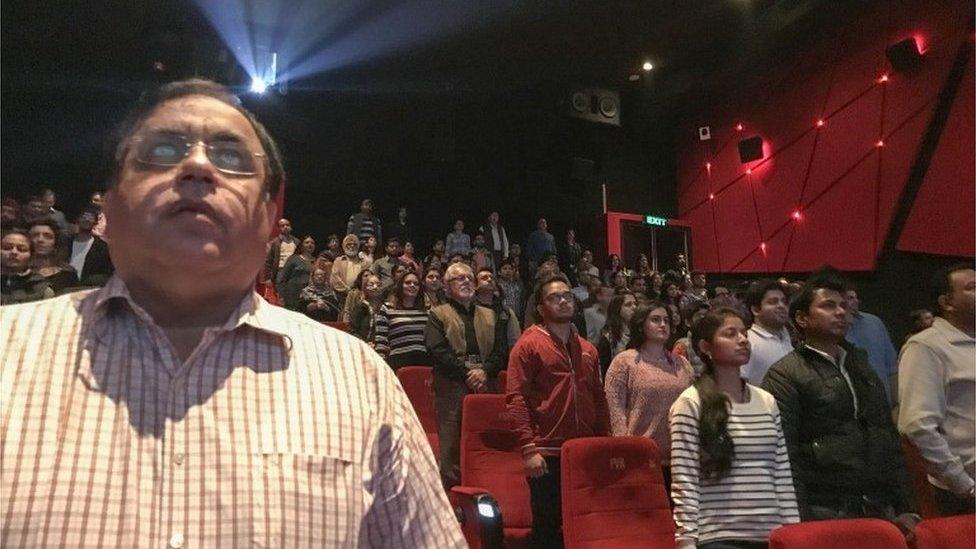 Audience members stand for the Indian national anthem before a movie starts at a cinema in New Delhi on December 4, 2016.