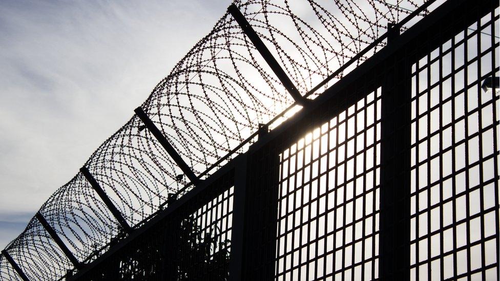 Stock image of barbed wire on top of a fence