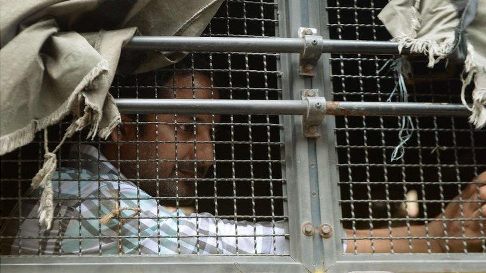 An Indian prisoner, convicted of involvement in the 2006 Mumbai train blasts, looks out from a police van on his way to a special court in Mumbai on September 16, 2015.