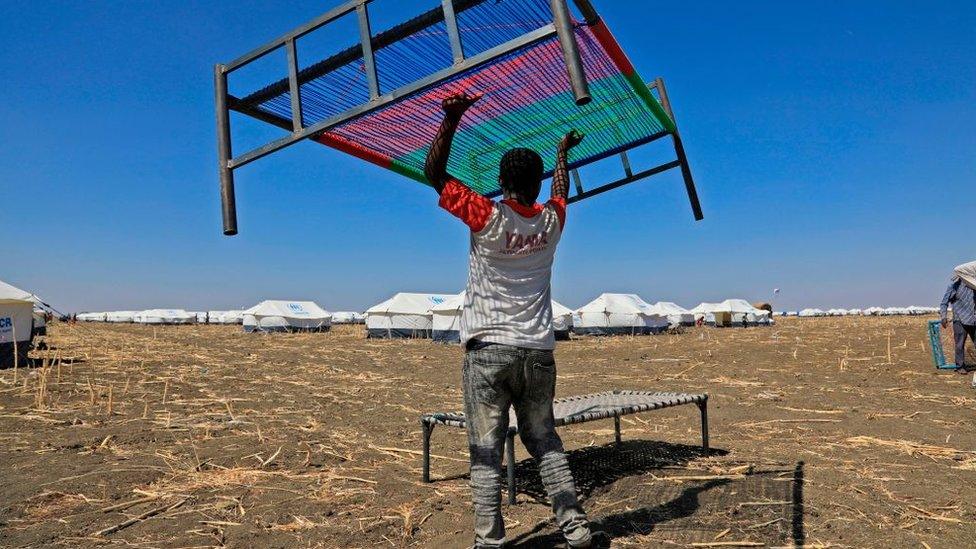 An Ethiopian refugee, who fled the Tigray conflict, carries a bed upon his arrival at the Tenedba camp in Mafaza, eastern Sudan on January 8, 2021, after being transported from the reception center.