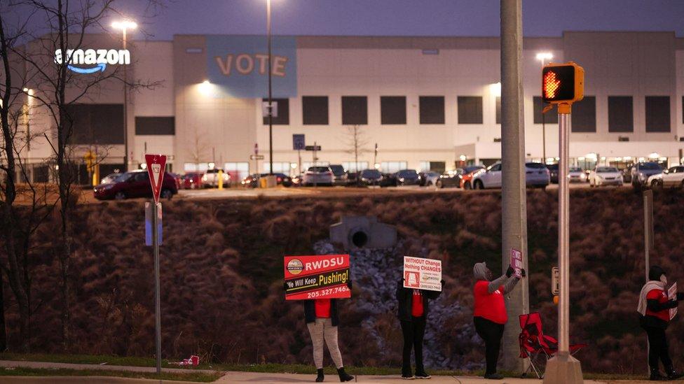 People affiliated with RWDSU (Retail, Wholesale and Department Store Union) hold signs supporting unionization in front of an Amazon facility on the first day of the unionization vote in Bessemer, Alabama, U.S., February 4, 2022