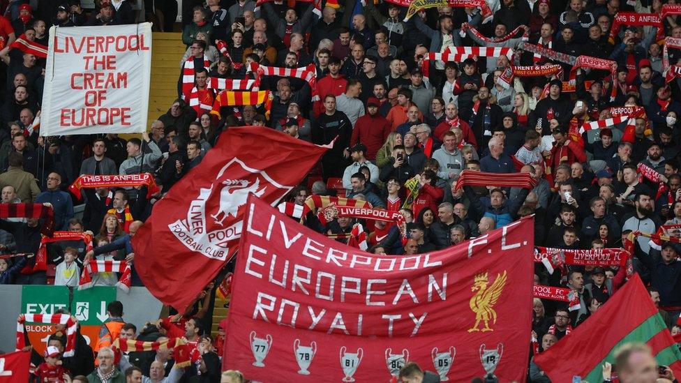 Liverpool fans holding scarves and flags