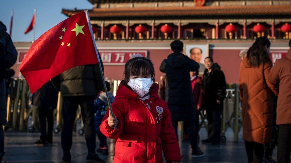 child-wearing-mask-holding-flag-tiananmen-square