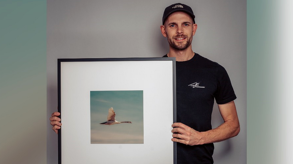 Taz Brotherton holding a framed photograph