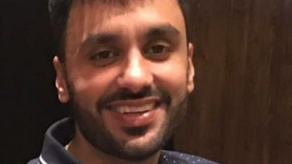 Jagtar Singh Johal, pictured before his arrest, is looking at the camera and smiling. He has short dark hear and a short beard, and is wearing a navy blue polo shirt.