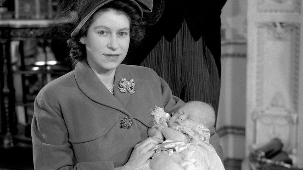 Princess Elizabeth holding her infant son, Prince Charles, after his christening ceremony at Buckingham Palace